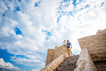 Moscow, Russia - August 21, 2016: A man with a child standing on the stone building on a background of blue sky with cloudsのeditorial素材