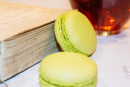 Two macarons dessert on a table near old books and a cup of black teaの写真素材
