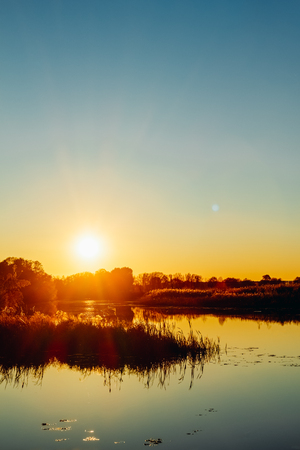Sunset on the river bank with reflection in the waterの写真素材