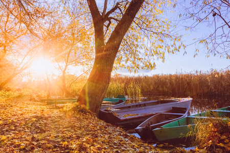 Sunset autumn sun in a river landscape with fishing boatsの写真素材