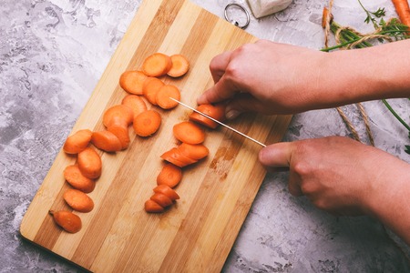Woman hands cut carrotsの写真素材