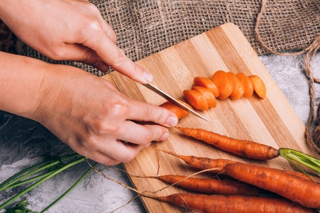 Cutting carrots by a girl on a boardの写真素材