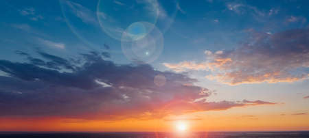 Panorama of a beautiful sky with the sun and lens flare on the clouds against the backdrop of a calm summer evening. Drone viewの写真素材