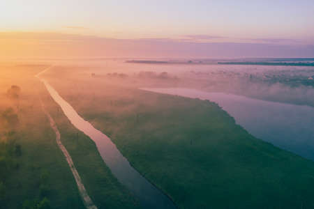 Beautiful foggy summer morning over fields with lakes and a river. View from aboveの写真素材