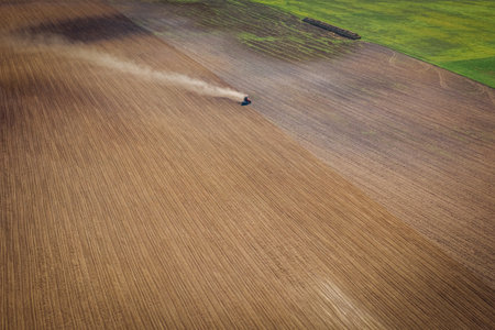Aerial view of an Agricultural Field with a Tractor plowing land for planting seasonの写真素材