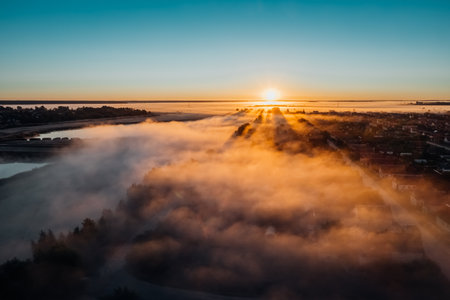 Sunrise with fog in autumn on lake. Rays of sun in fogの写真素材