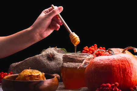 Hand Drizzling Honey on Rustic Autumn Pumpkin Still Life for a Festive and Cozy Seasonal Decorの写真素材