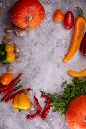 Arrangement of autumnal vegetables, including peppers and garlic, on a rustic grey backgroundの写真素材