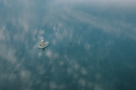 A breathtaking aerial view showcases a small boat sailing peacefully on calm and serene watersの写真素材