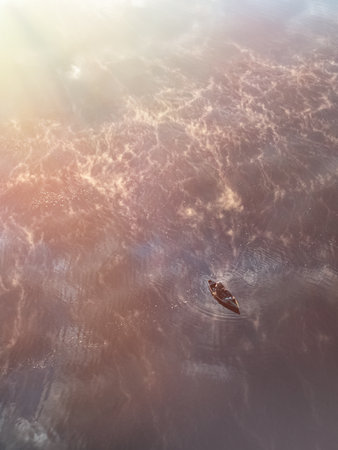 Enjoy a Serene Sunset Glowing Over Tranquil Waters While Observing a Small Boat Gliding Smoothlyの写真素材