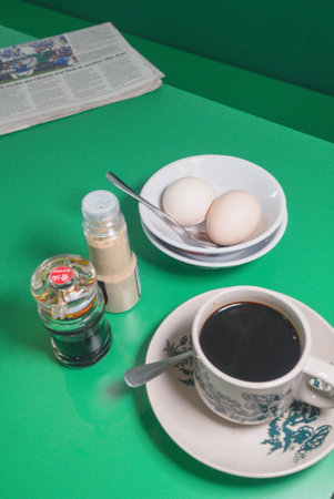 Eggs, coffee and newspaper on green table. Malaysian Breakfast conceptの写真素材