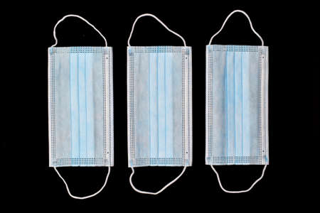 Disposable surgical masks or blue colored new medical respirators. COVID-19 prevention. H1N1, H5N1 safety measures. Isolated on black background.の写真素材