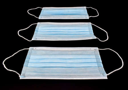 Disposable surgical masks or blue colored new medical respirators. COVID-19 prevention. H1N1, H5N1 safety measures. Isolated on black background.の写真素材