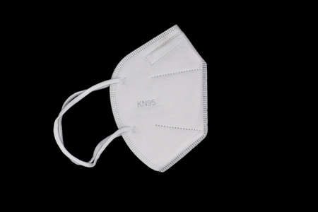 Disposable KN-95 mask or white colored new medical mask. COVID-19 prevention. H1N1, H5N1 safety measures. Isolated on black background.の写真素材