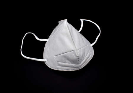 Disposable KN-95 mask or white colored new medical mask. COVID-19 prevention. H1N1, H5N1 safety measures. Isolated on black background.の写真素材