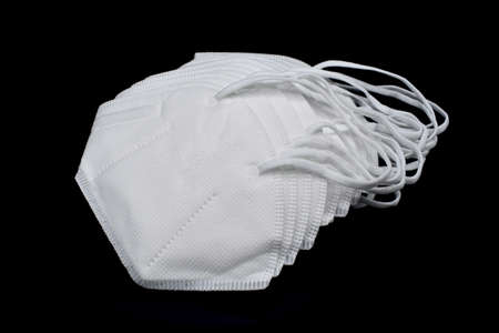 Disposable KN-95 masks or white colored new medical masks. COVID-19 prevention. H1N1, H5N1 safety measures. Isolated on black background.の写真素材