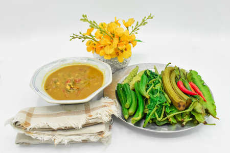 Myanmar or Burmese Traditional Fish Preserve Sauce, Ngapi yay and Fresh Vegetables, chilies , bottle gourd leaves, bitter gourd, flat green peas in steel plate. Isolated on whiteの写真素材