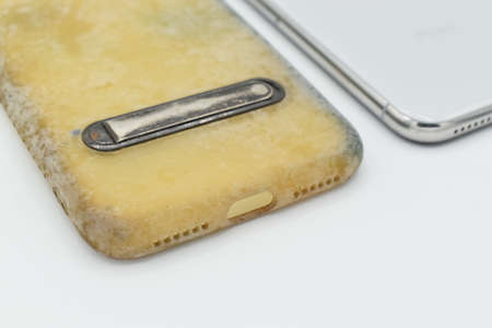 Old and dirty silicon phone case due to yellow stains and mold. Isolated on white background. Closeup view.の写真素材