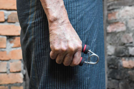 Southeast asian, Myanmar old man gripping hand exercise gripper.の写真素材
