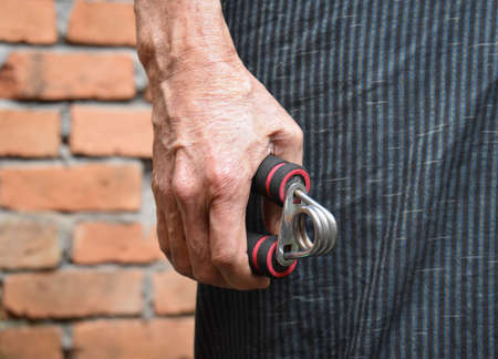 Hand of Southeast asian, Myanmar old man gripping hand exercise gripper.の写真素材