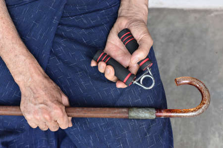 Southeast asian, Myanmar old man gripping hand exercise gripper.