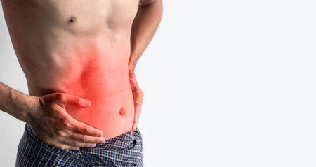 Asian young man suffering from abdominal pain. It can be caused by stomach ache, enteritis, colitis, appendicitis, hepatitis, pancreatitis, food poisoning, etc.の写真素材