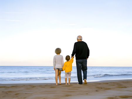 Grandfather walking together with his grandchildren at the beach. Concept of happy grandfather day, grandparents day.の素材