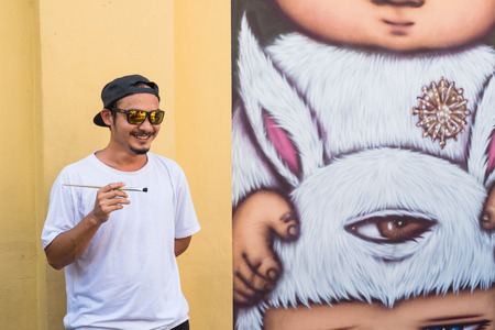 Portrait of Alex Face. a famous Thai street artist and graffiti with his mural artwork of an iconic character 'Mardi'のeditorial素材