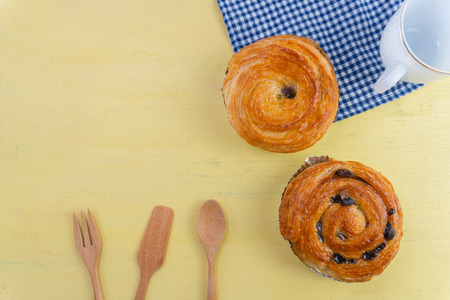 Raisin danish pastry on the yellow wood and blue gingham check cloth. Colourful tasty sweet bakery.の写真素材
