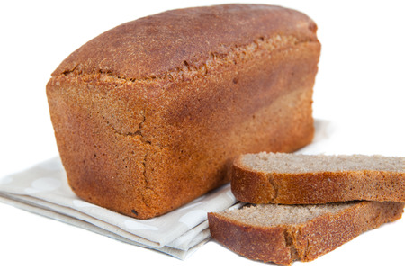 Loaf of fresh bread and a couple of pieces of bread on doily isolated on white