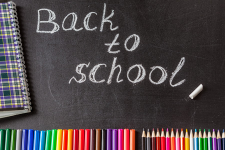 Back to school background with colorful felt tip pens, pencils, notebook and the title Back to...