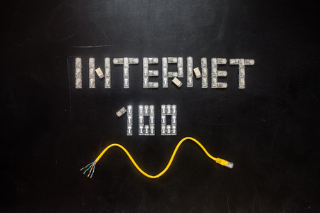Word "Internet" and numeral "100", made of connectors RJ45 and yellow patch cord isolated over the black scratched board background.の写真素材