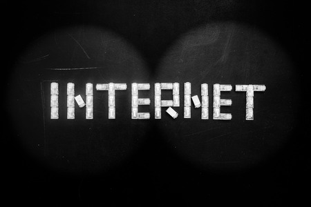 View from binoculars on the composition word "Internet" made of connectors RJ45  isolated over the black scratched board background.の写真素材