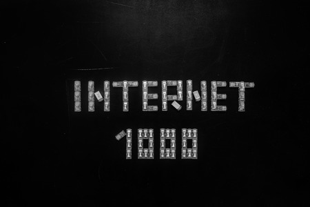 Word "Internet" and numeral "1000", made of connectors RJ45 for LAN isolated over the black scratched board background.の写真素材