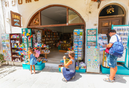 Rethymnon, Island Crete, Greece, - July 1, 2016: Family near the souvenir store "Book spot". There are  mother is taking photo with your daughter who wants to get toys and father is considering bookのeditorial素材