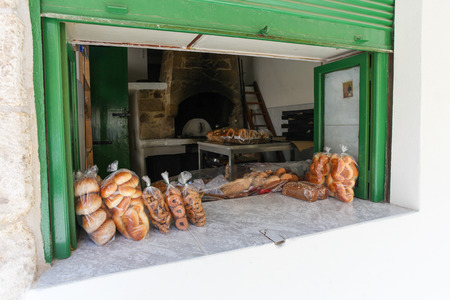Rethymnon, Island Crete, Greece, - July 1, 2016: Window of bakery with fresh and  tasty muffins, pastry and  bread  on the street of the old town's part of city Rethymnonのeditorial素材