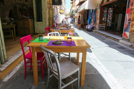 Rethymnon, Island Crete, Greece, - June 23, 2016: Tables and chairs of cafe are on the narrow street of Rethymnon (part of Old Town)のeditorial素材