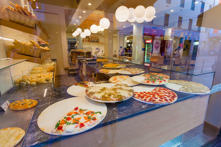 MILAN, ITALY - September 12, 2016: Tasty  pieces of pizza and delicious focaccia  in the street pizzeria window behind glass in Milan and reflection of street in glassのeditorial素材
