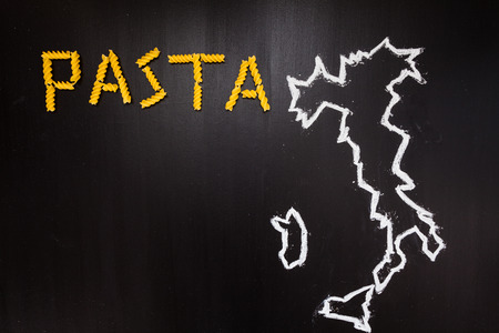 Word pasta made of dry pasta on the black background with frame of country Italy written by chalkの写真素材