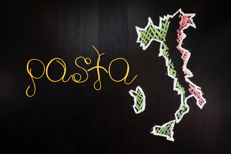 Word pasta made of cooked spaghetti on the black background with frame of country Italy written by chalkの写真素材