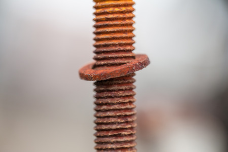 Close-up image of old rusty screw and bolt on steel surface with blurred backgroundの写真素材