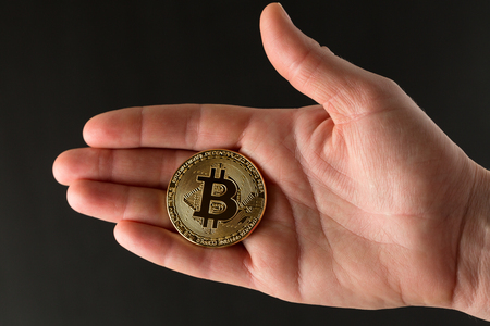 Bitcoin on the human hand and black background. Physical bit coins. Digital currency. Cryptocurrency. Golden coins with bitcoin.の写真素材