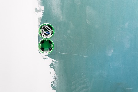 Unfinished double electrical mains outlet socket with electrical wires installed in plasterboard or drywall for gypsum walls in apartment is under construction and remodelingの写真素材