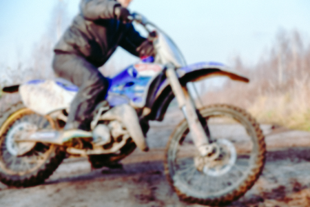 Blurred motocross racer accelerating in dirt track on the mountain motocross race in dirt track in day time. Blurred background with bokeh effect.の写真素材