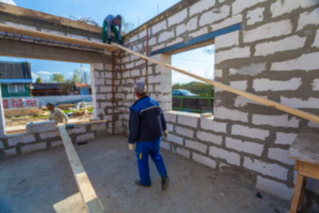 Blurred  building is under construction with roofing and the materials for construction and workers. Blurred background of construction concept  with bokeh effectの写真素材