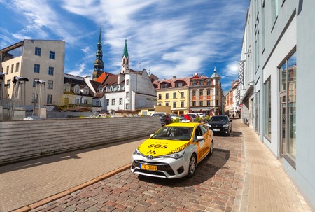 RIGA, LATVIA - MAY 06, 2017: View on the  old street  with yellow taxi car that is  located in the city center of Riga.のeditorial素材