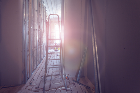 Ladder and construction tools and interior of room during of installing of plasterboard or drywall  for making gypsum walls on the wall in an apartment is under construction, remodeling, renovation,  restoration, reconstruction, overhaul.の写真素材