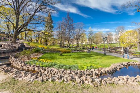 RIGA, LATVIA - MAY 06, 2017: View on  pathways with blossom trees, bushes and walking  people in The Park Bastion Hill that is located in the city center of Riga. Bastion Hill is one of the most romantic places in central Rigaのeditorial素材
