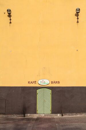 RIGA, LATVIA - MAY 06, 2017: View on the yellow wall with two lamps and the enter to cafe is located in the city center of Riga.のeditorial素材