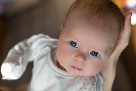 Mother hold in hands her daughter - adorable and cute little baby girl with  blue eyes